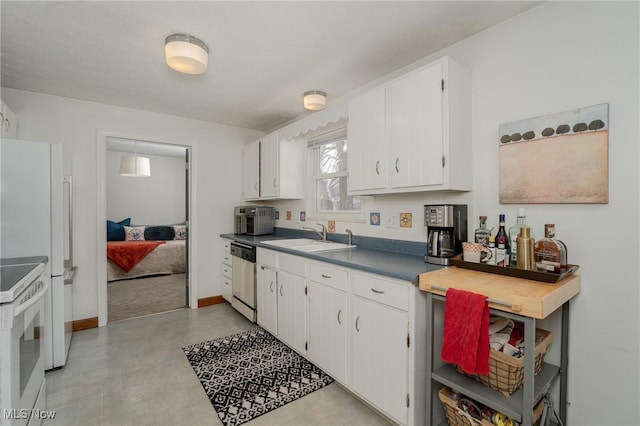 kitchen with white appliances, white cabinetry, and a sink