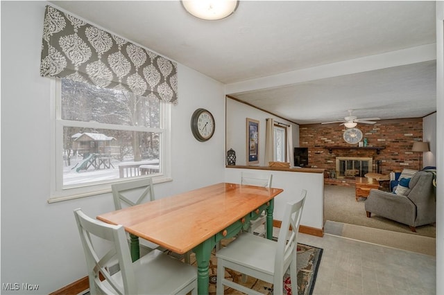 dining room featuring light carpet, ceiling fan, a fireplace, and baseboards