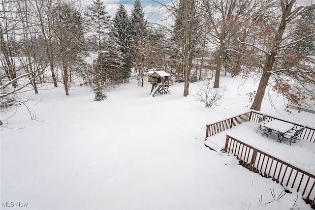 yard layered in snow featuring a playground