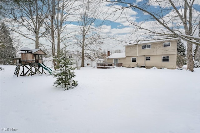 yard covered in snow with a playground and a wooden deck