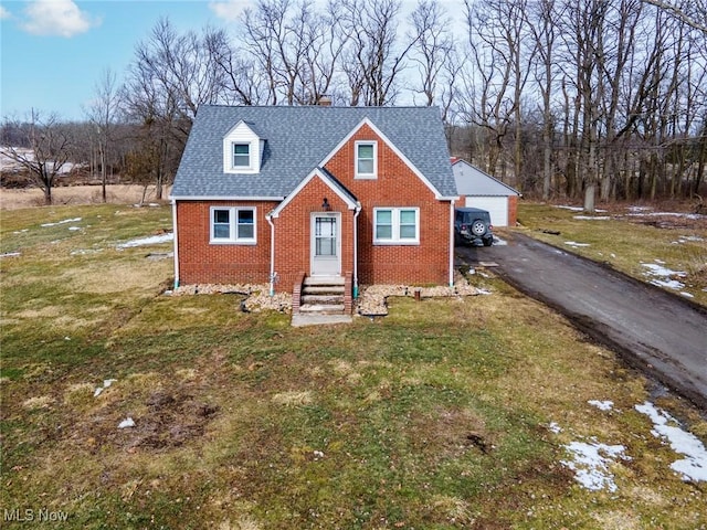 view of front of property with a shingled roof, a front yard, brick siding, and a garage