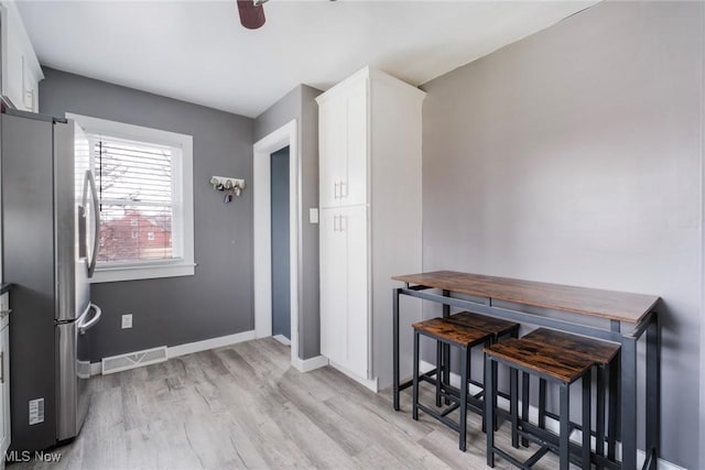 interior space with baseboards, ceiling fan, visible vents, and light wood-style floors