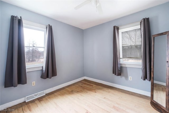 spare room with a ceiling fan, light wood-style flooring, visible vents, and baseboards