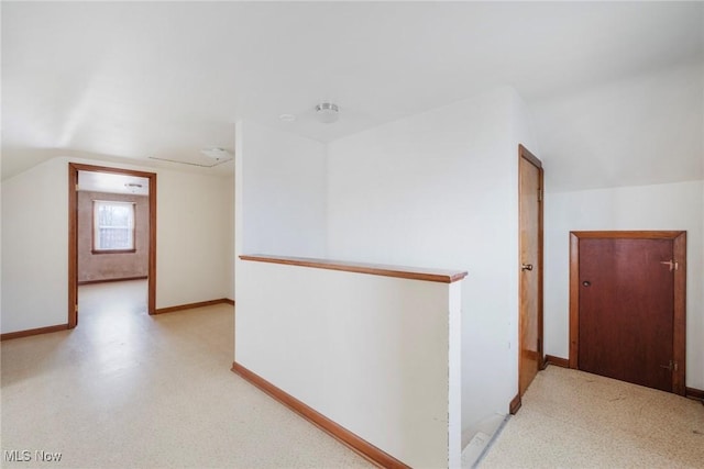 corridor featuring vaulted ceiling and baseboards