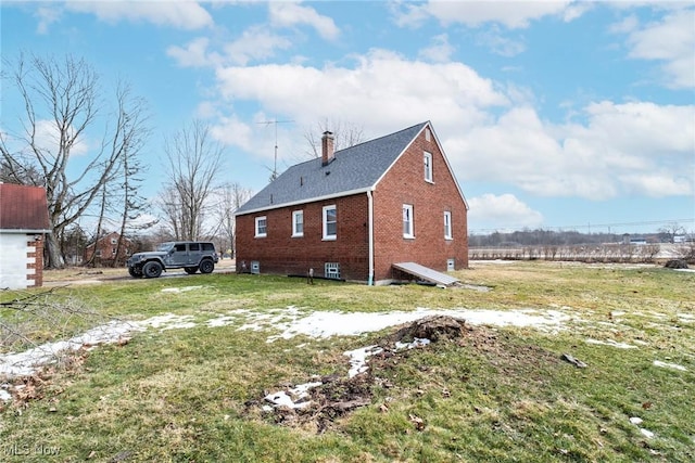 view of side of property featuring a chimney, a lawn, and brick siding