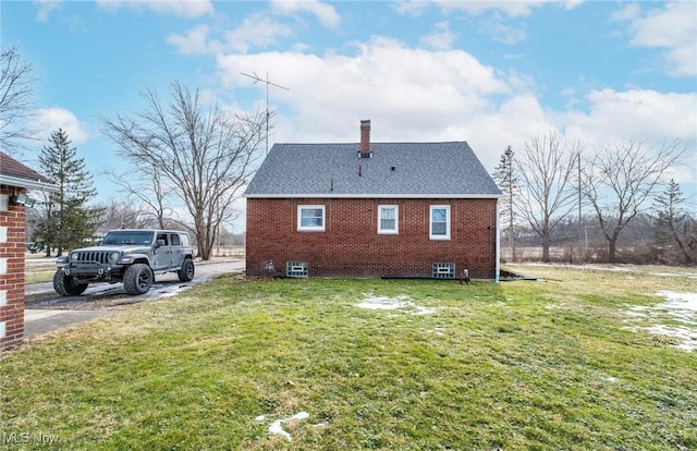 view of side of home featuring brick siding, a lawn, a chimney, and roof with shingles