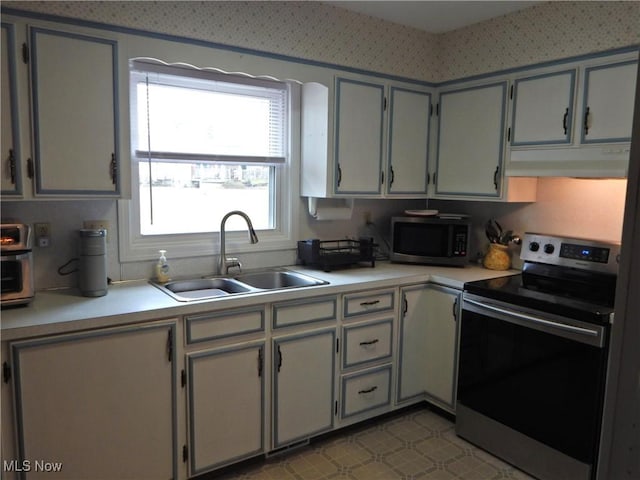 kitchen featuring light countertops, appliances with stainless steel finishes, a sink, and under cabinet range hood