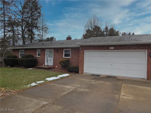 single story home featuring a garage, brick siding, driveway, a chimney, and a front yard