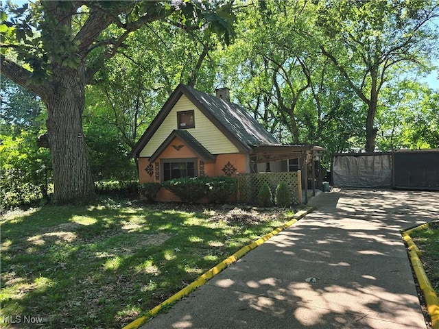 view of front of home featuring a chimney, concrete driveway, a front yard, a gate, and fence