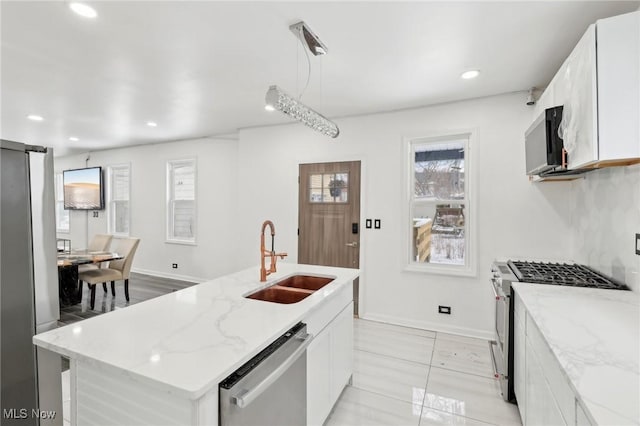 kitchen with pendant lighting, a center island with sink, appliances with stainless steel finishes, white cabinets, and a sink