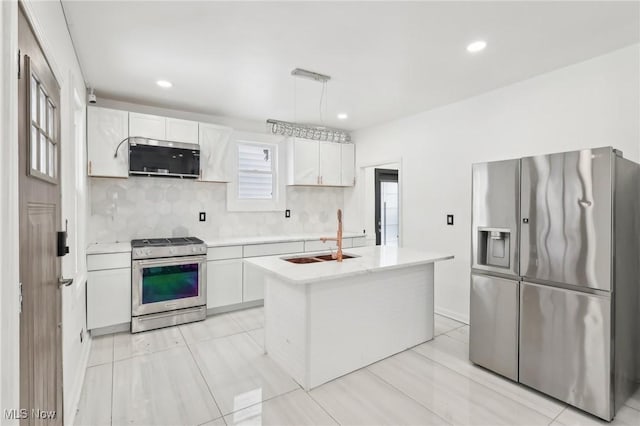 kitchen with decorative light fixtures, light countertops, appliances with stainless steel finishes, a kitchen island, and a sink