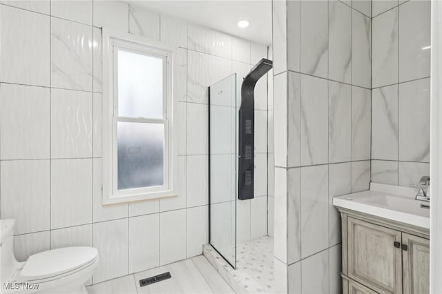 full bathroom featuring a stall shower, visible vents, toilet, vanity, and tile walls