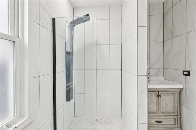 bathroom featuring tiled shower, tile walls, and vanity