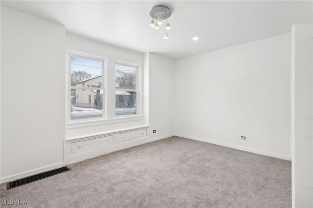 empty room featuring light colored carpet, visible vents, and baseboards