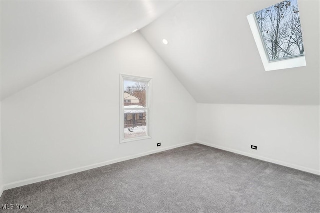 additional living space featuring carpet floors, vaulted ceiling with skylight, and baseboards