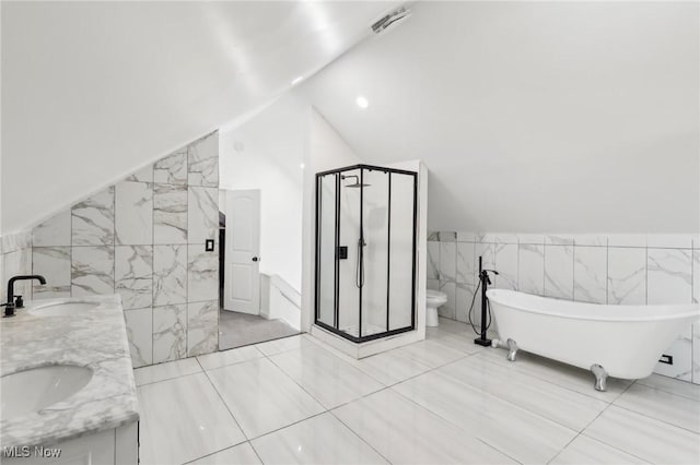 full bathroom with vaulted ceiling, a sink, toilet, and tile walls