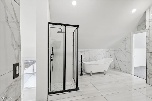 full bathroom with lofted ceiling, a shower stall, tile walls, and a freestanding bath