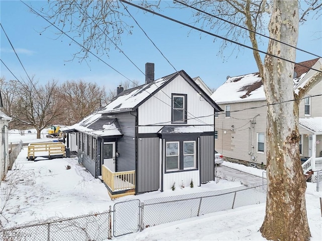 view of front of house featuring covered porch, a chimney, fence, and board and batten siding