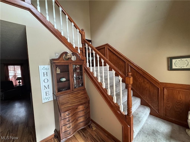 stairs with a towering ceiling, baseboards, and wood finished floors