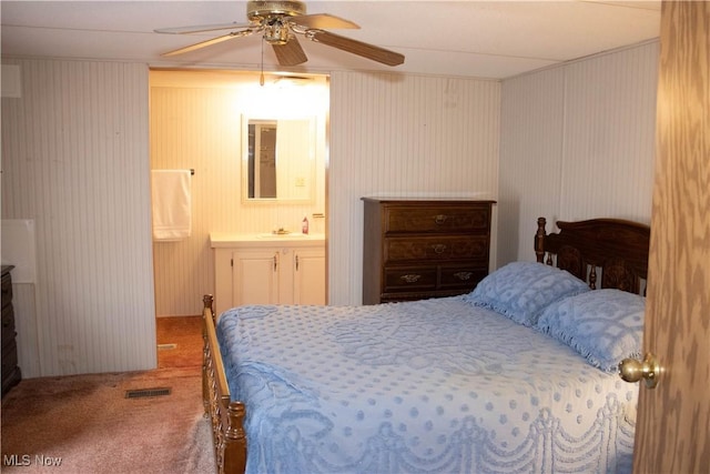 bedroom with ensuite bathroom, a sink, visible vents, a ceiling fan, and carpet