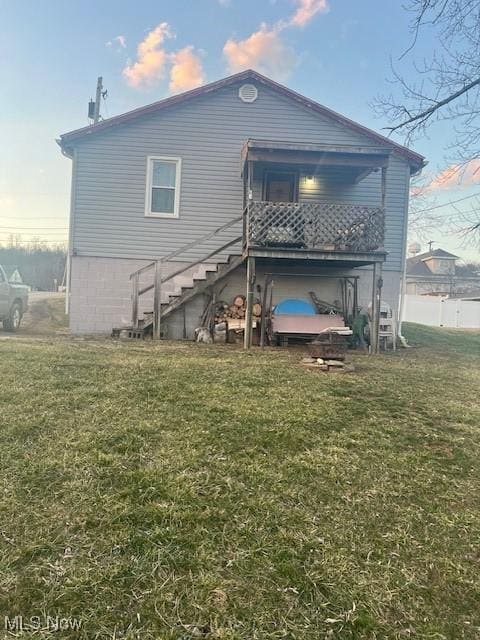 rear view of property with stairs and a lawn