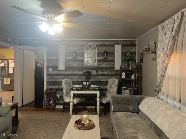 living area featuring wooden walls and a ceiling fan