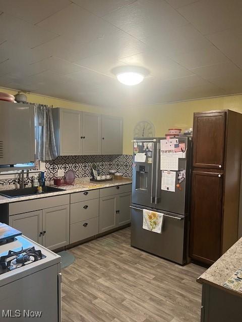 kitchen with light countertops, light wood-style floors, a sink, and stainless steel fridge with ice dispenser