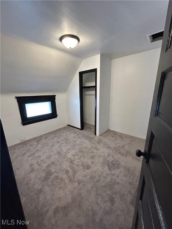 bonus room featuring light colored carpet, vaulted ceiling, and visible vents