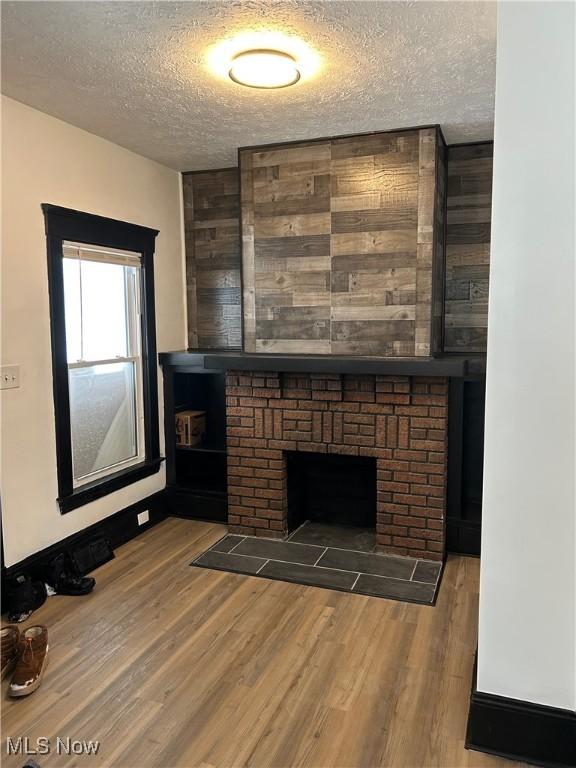 living area featuring a textured ceiling, dark wood-style flooring, and a fireplace