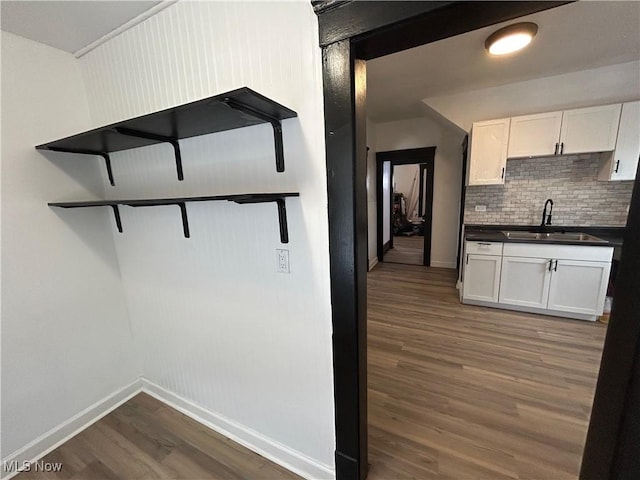 kitchen with white cabinets, dark countertops, dark wood-style flooring, open shelves, and a sink