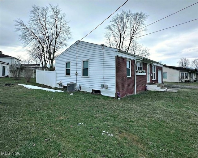 view of property exterior with brick siding, fence, central AC, and a lawn