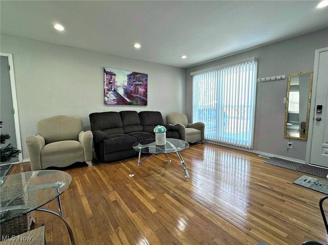 living room with recessed lighting, visible vents, baseboards, and wood finished floors