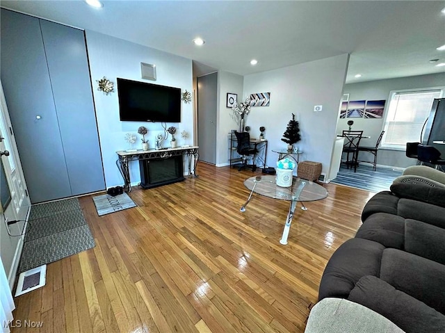 living room featuring light wood-type flooring, baseboards, visible vents, and recessed lighting