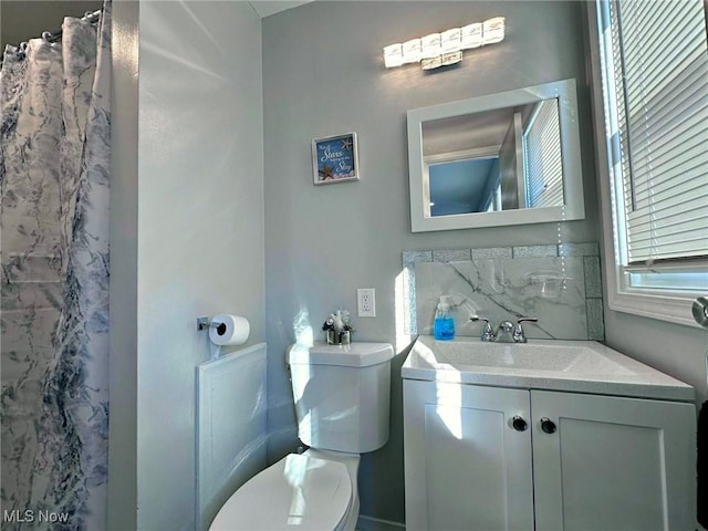 full bath with toilet, decorative backsplash, and vanity