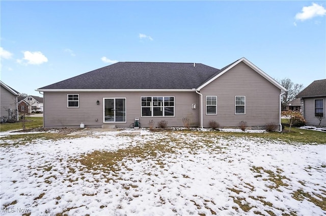 snow covered property with roof with shingles