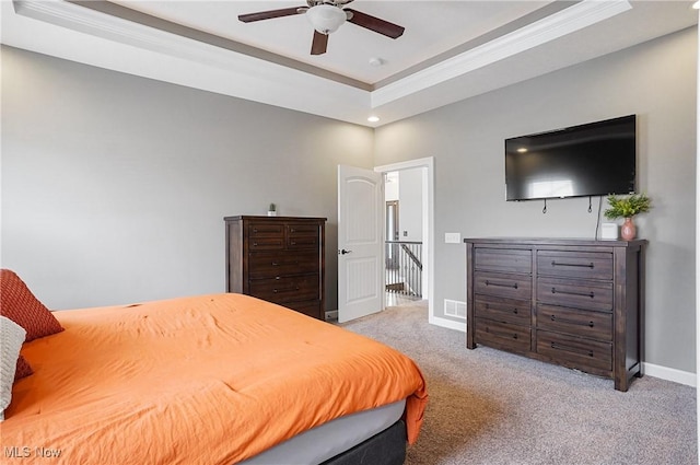 bedroom featuring crown molding, a raised ceiling, light colored carpet, a ceiling fan, and baseboards