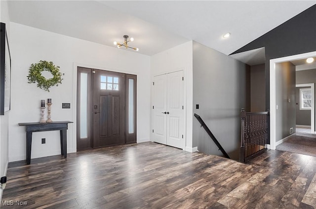 foyer with vaulted ceiling, an inviting chandelier, dark wood finished floors, and baseboards