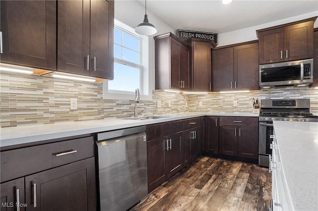 kitchen with stainless steel appliances, light stone counters, a sink, and pendant lighting