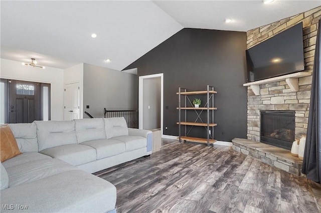 living area with lofted ceiling, a stone fireplace, wood finished floors, and baseboards