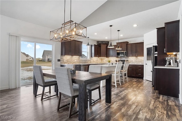 dining area with lofted ceiling, dark wood-style flooring, an inviting chandelier, and recessed lighting