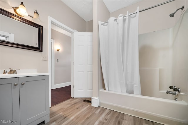 full bath with shower / tub combo, vanity, baseboards, and wood finished floors