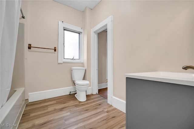 bathroom featuring shower / bathtub combination with curtain, wood finished floors, toilet, and baseboards