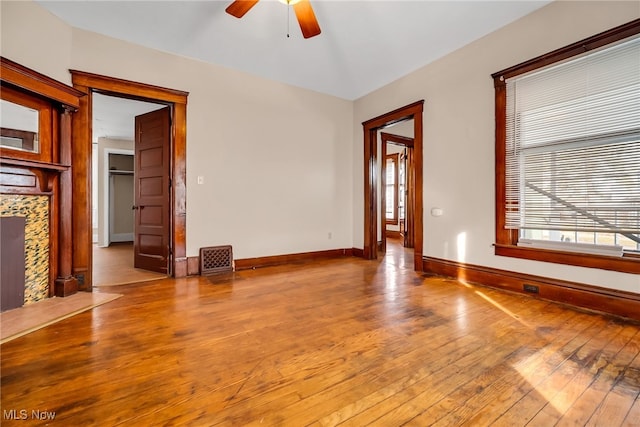 unfurnished living room featuring a ceiling fan, a fireplace, hardwood / wood-style flooring, and baseboards