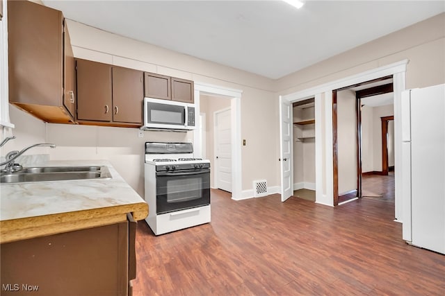 kitchen with white appliances, visible vents, dark wood-style flooring, light countertops, and a sink