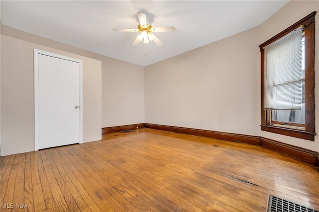 empty room with light wood-style flooring, visible vents, baseboards, and a ceiling fan