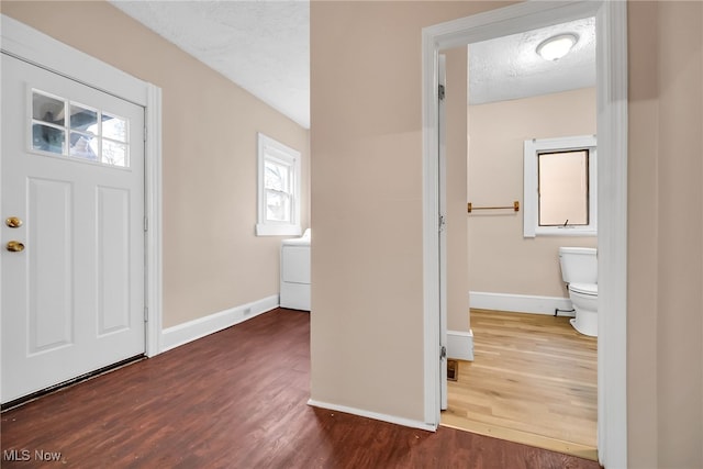 foyer with a textured ceiling, washer / clothes dryer, wood finished floors, and baseboards