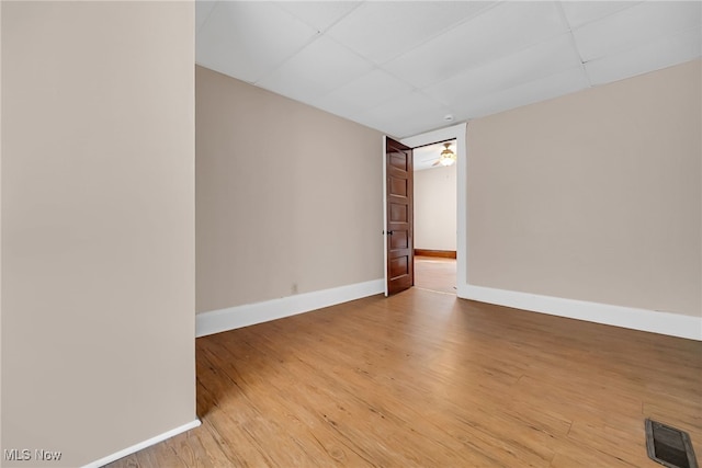 spare room with a paneled ceiling, visible vents, light wood-style flooring, and baseboards