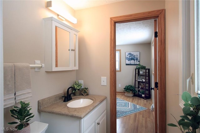 half bathroom featuring vanity, toilet, and wood finished floors