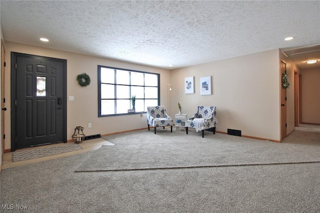 foyer featuring recessed lighting, light carpet, a textured ceiling, and baseboards