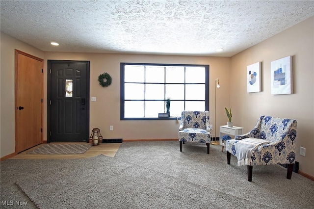 entrance foyer featuring a textured ceiling, light colored carpet, and baseboards